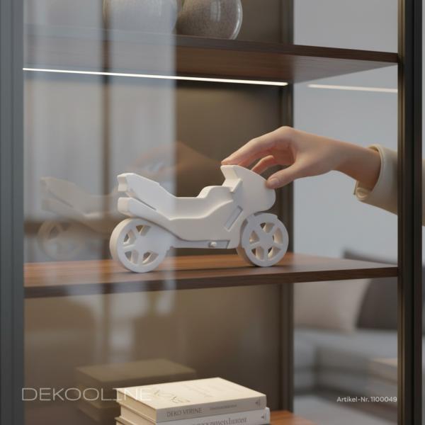 Weißes Raysin Deko‑Motorrad dekorativ auf Regal platziert, minimalistisches Wohnambiente.